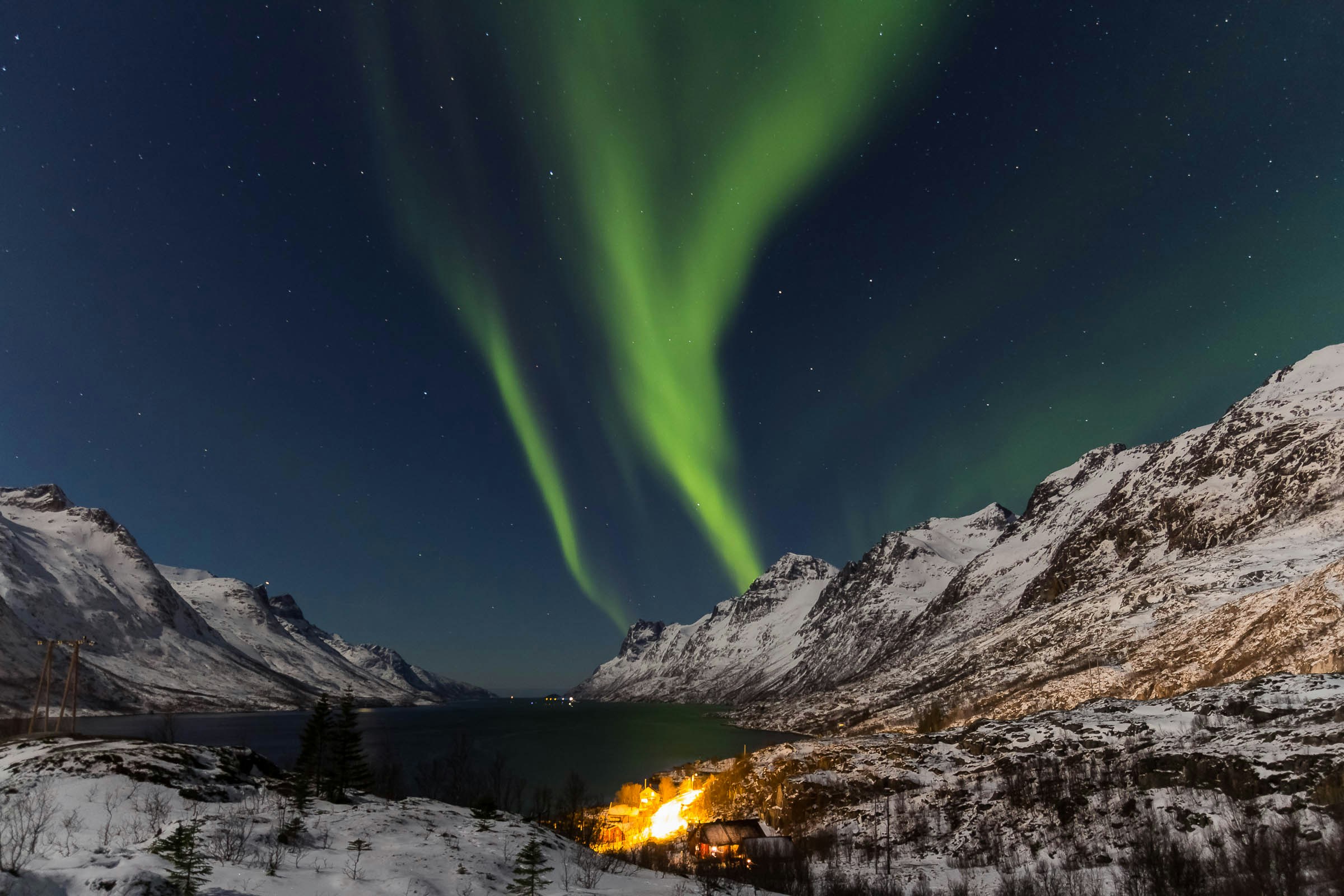 green lights in the sky over mountains and water tromso inverno